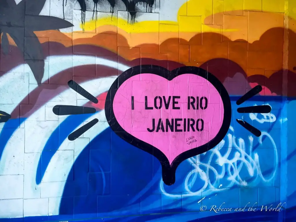 A vibrant graffiti on a wall featuring a heart shape with the phrase "I LOVE RIO JANEIRO" in bold letters, surrounded by black doodle-like marks. The background has abstract shapes in various colours. 3 days in Rio de Janeiro is a great amount of time to experience the city.