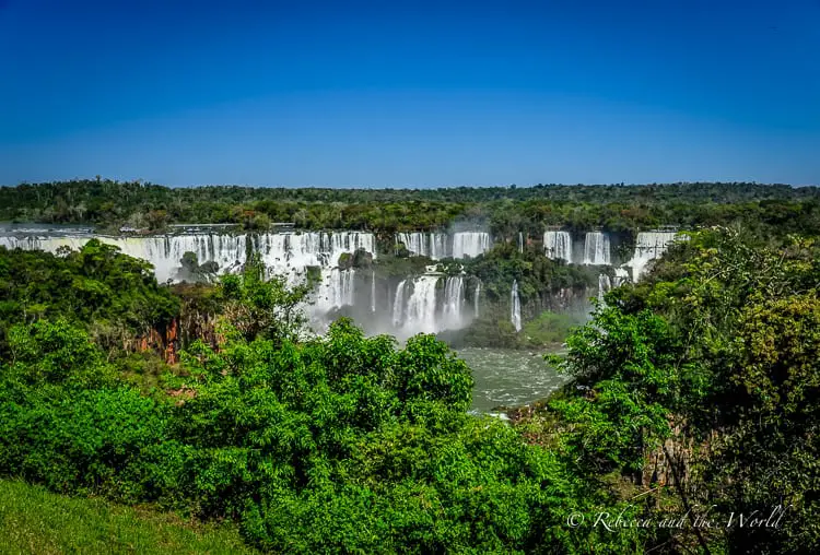 The best time to visit Iguazu Falls is April and May and September and October. The waterfalls can be seen in the distance, in between lush rainforest.