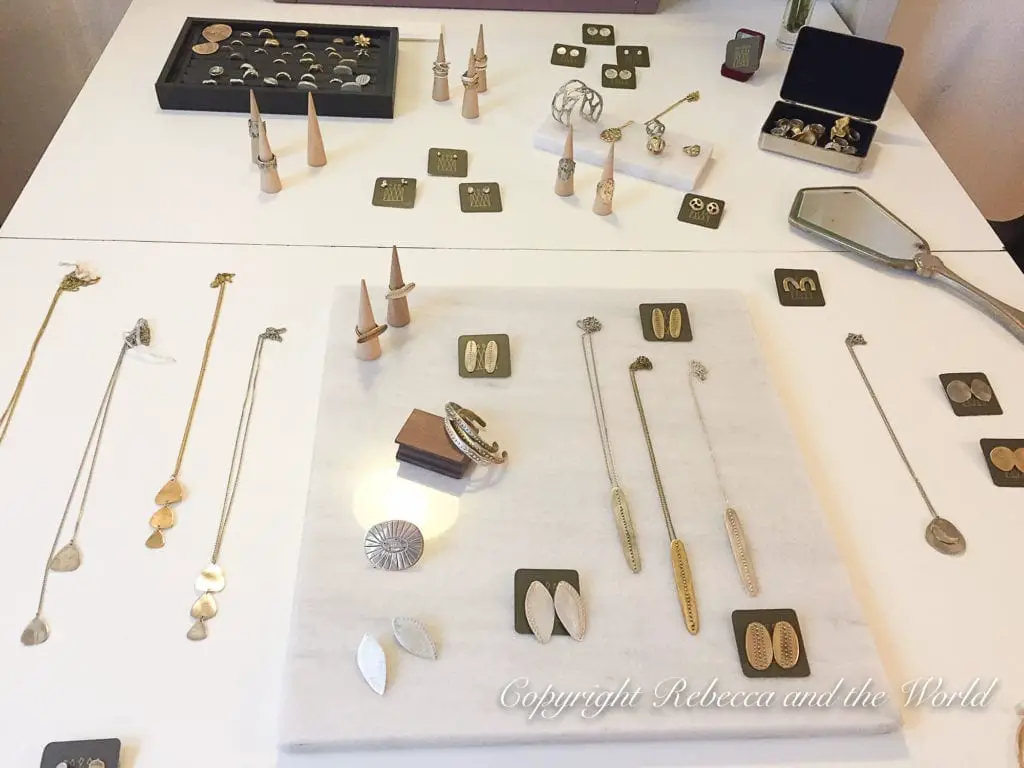 A display of jewelry on a white table, consisting of necklaces, earrings, and rings. The jewelry features gold and silver tones with minimalist designs. Some pieces are presented on small stands or laid out neatly on the table. This is some of the amazing jewellery you can buy on a Buenos Aires shopping trip.