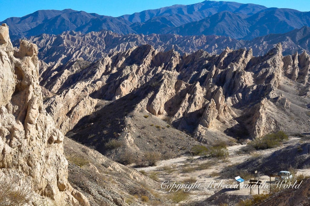 Rugged, sharply eroded mountain terrain with sparse vegetation under a bright blue sky in the arid landscape of North Argentina. The Quebrada de las Flechas is one of the most out-of-this-world landscapes you'll see on a north Argentina road trip - it resembles quivers of arrows.