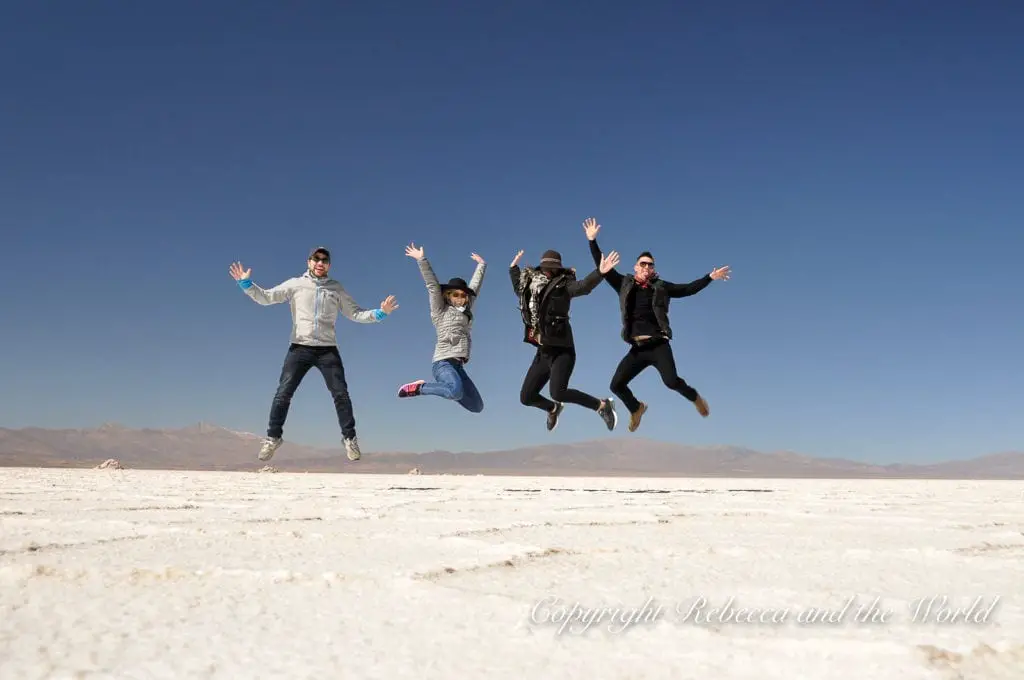 Four people - the author of this article, her husband and two friends - mid-jump on a salt flat, casting long shadows on the white ground, with a clear blue sky overhead in North Argentina. Visit the Salinas Grandes in northwest Argentina - the second-largest salt pan in the world.