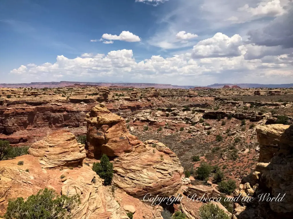 A landscape of Canyonlands National Park with intricate rock formations and vast canyons under a partly cloudy sky.