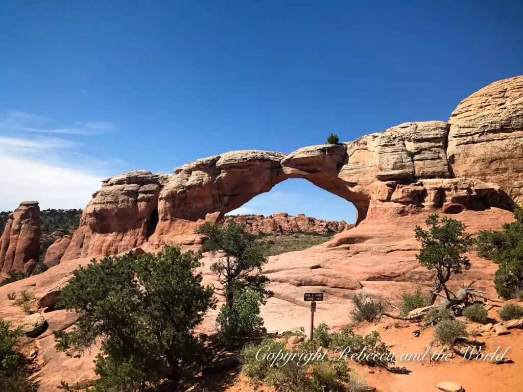 The North Window arch in Arches National Park with a clear view through the opening to the rock formations beyond, under a clear blue sky.
