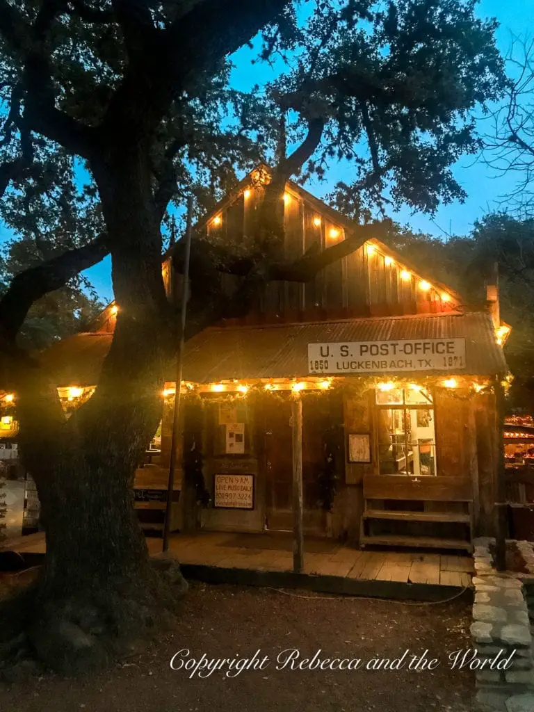 The quaint Luckenbach Post Office illuminated by string lights at dusk, reflecting the historic and cozy charm of small-town Texas.