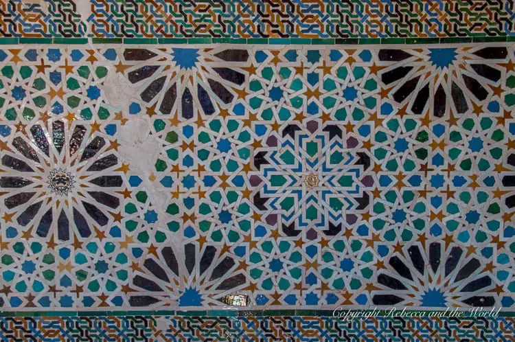 Close-up of traditional Islamic star-shaped tile work with intricate patterns in blue, white, and yellow, from the Alhambra’s walls. You'll take hundreds of photos on a visit to the Alhambra in Granada, Spain - the details are incredible.