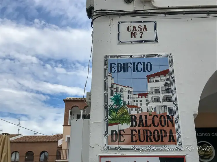 A ceramic tile on a building displaying "Edificio Balcón de Europa" with an illustration of a coastal building scene.