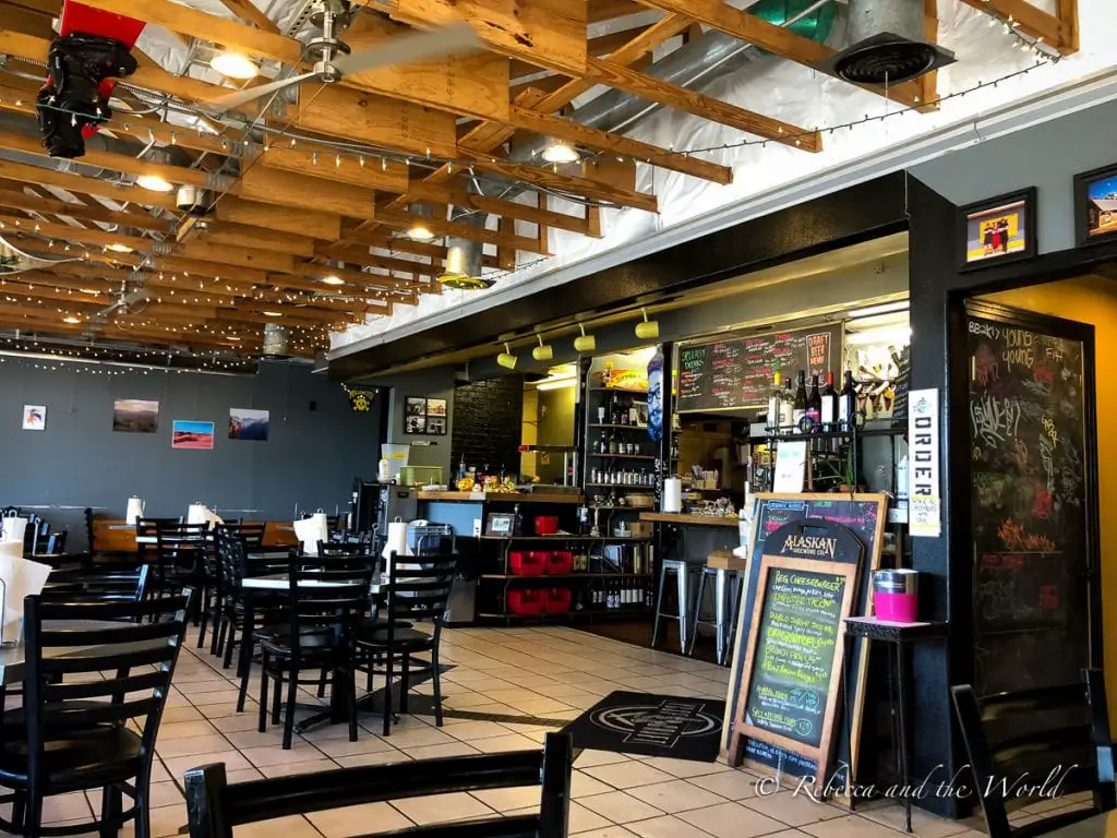 Interior of a casual dining restaurant in Amarillo with wooden beams, tables and chairs set up for guests, and a chalkboard menu listing various dishes. Yellow City Street Food is one of the best places to eat in Amarillo, Texas.