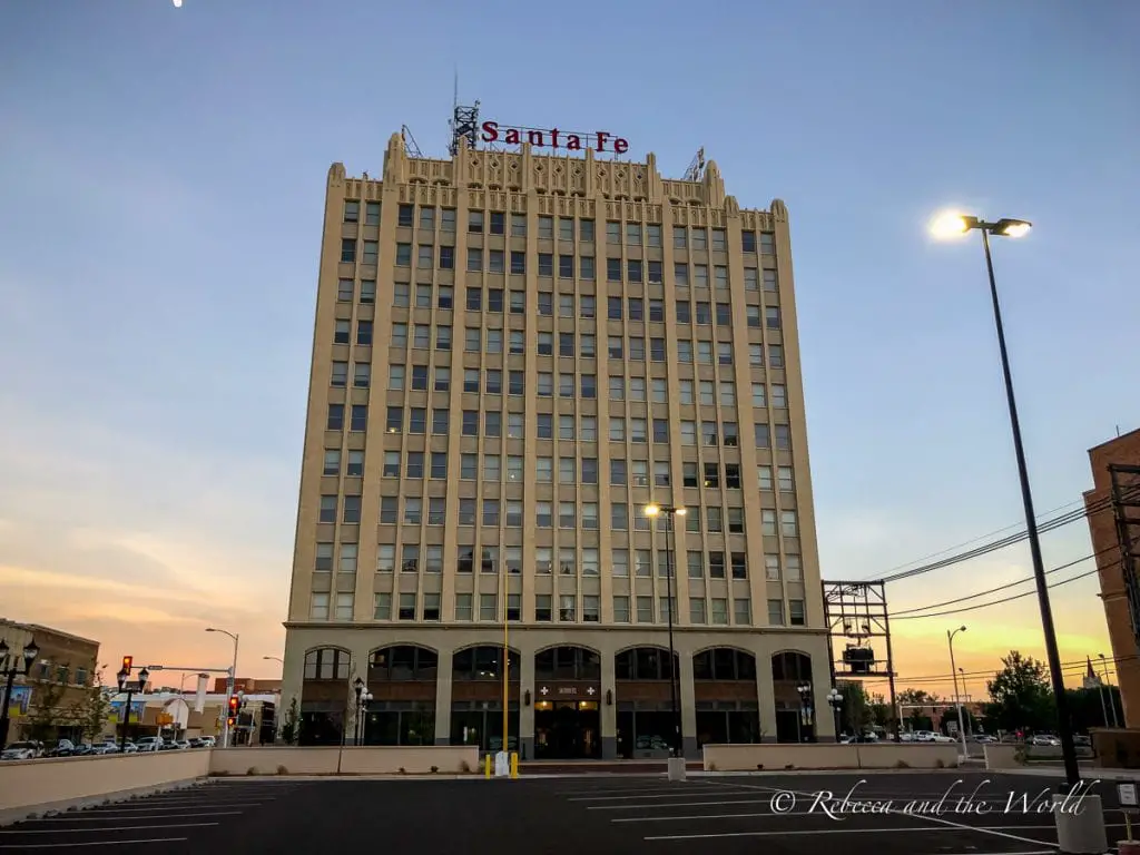 The imposing Santa Fe Building in Amarillo, Texas, captured at dusk with lights glowing from street lamps and a clear twilight sky. One of the best things to do in Amarillo, Texas, is enjoy the beautiful art deco buildings.