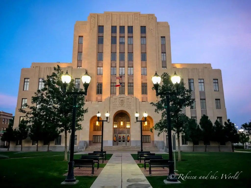 The Potter County Courthouse in Amarillo illuminated by outdoor lights, with a well-manicured lawn and pathway leading to the entrance. One of the best things to do in Amarillo, Texas, is enjoy the beautiful art deco buildings.