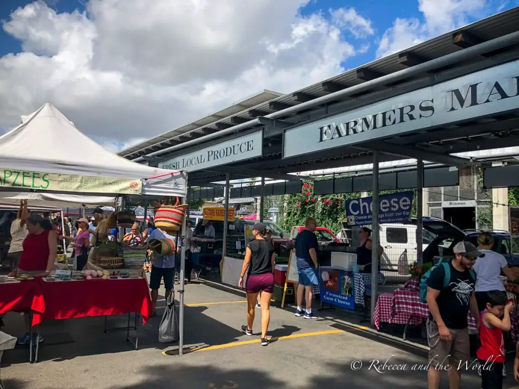 A bustling farmer's market with tents and vendors selling local produce, cheeses, and handmade goods under a clear sky. Stop by the New Braunfels Farmers Market to pick up local produce, crafts, handmade goods and food.