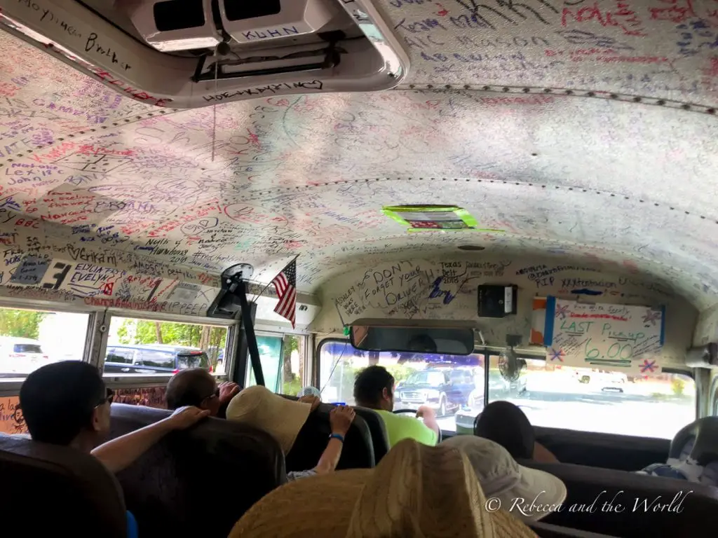 Interior of a bus with the ceiling covered in handwritten signatures and messages. Passengers are seated, looking ahead. River outfitters provide shuttles to and from the river access points.