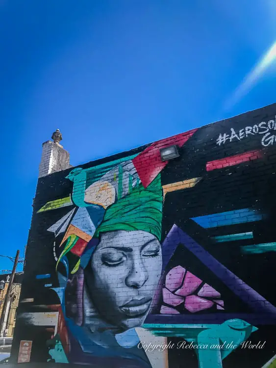 A vibrant mural in Deep Ellum featuring the face of singer and Dallas resident Erykah Badu with colourful geometric shapes, under clear blue skies.