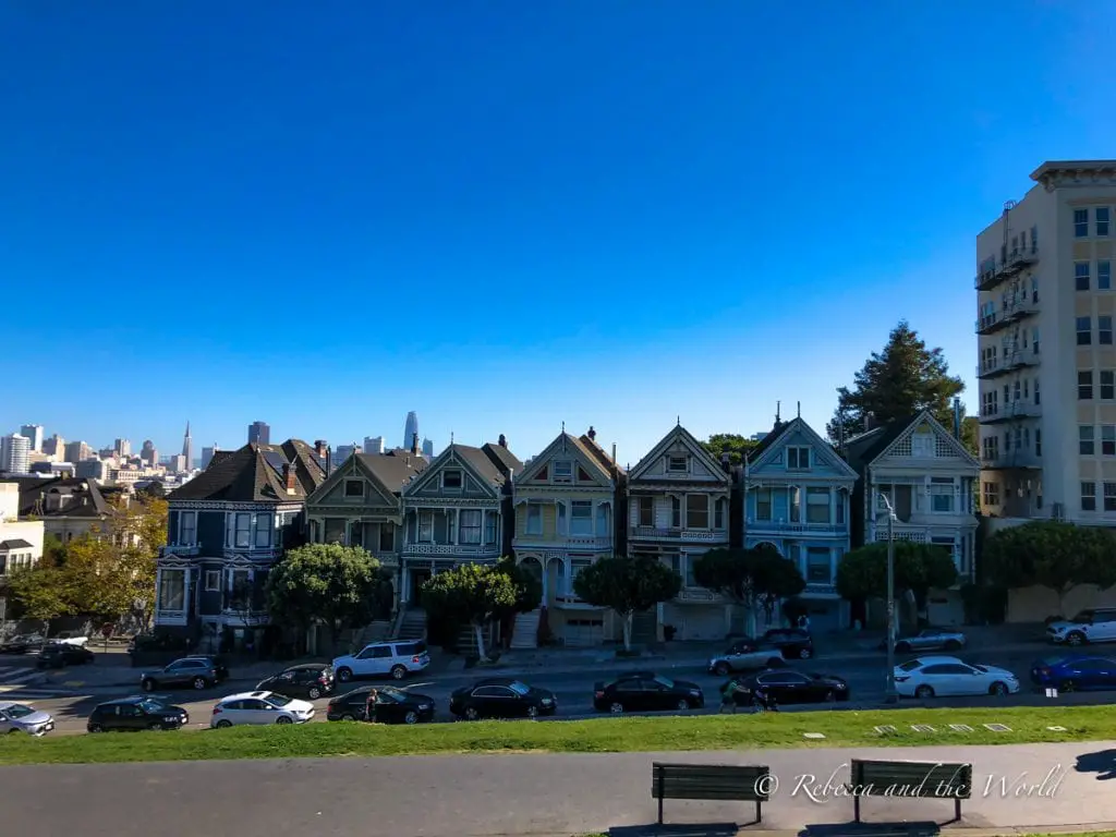 A row of iconic Victorian houses in San Francisco, known as the Painted Ladies, with the city skyline in the background under a clear blue sky. No visit to San Francisco is complete without stopping by the famous Painted Ladies
