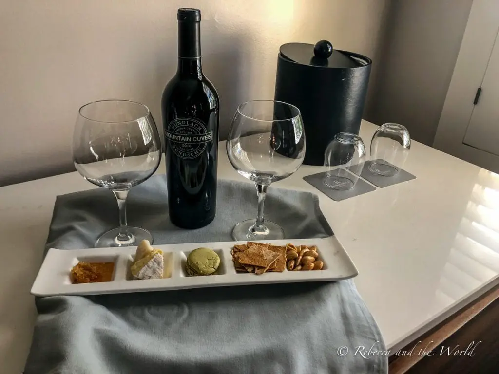 A wine tasting set up on a white table with two wine glasses, a bottle labeled 'Mountain Cuvee,' and a tasting plate with cheese, crackers, macarons and nuts. I highly recommend staying at The Lodge at Sonoma Resort - we were completely spoiled on our wedding anniversary!
