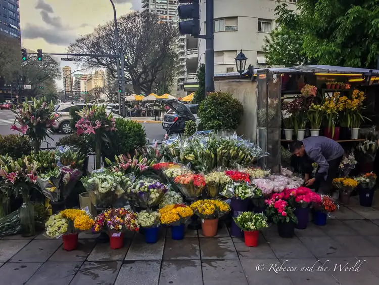 Buenos Aires street corner with buckets of colourful flowers next to a covered flower stall. Buenos Aires is a must-do if you have two weeks in Argentina.