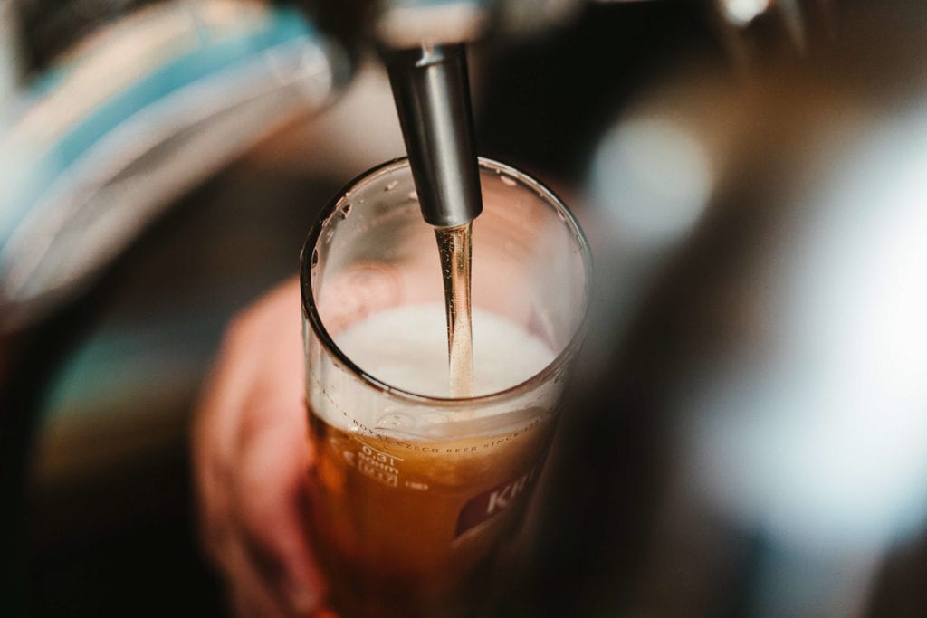 Close-up of a beer tap dispensing amber-colored beer into a pint glass, showcasing the foam head forming on the drink. Beer lovers will find plenty of great breweries in San Diego to enjoy.