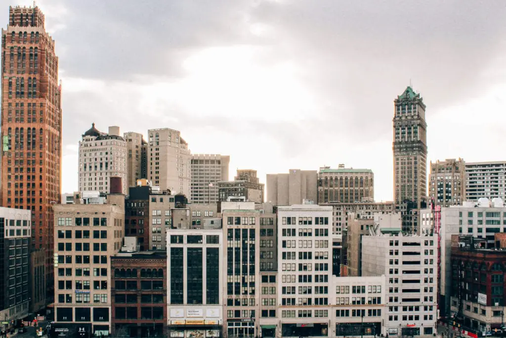 View of Detroit's downtown skyline with a mix of historic and modern buildings under a cloudy sky. A weekend in Detroit should be on your schedule so you can discover how this city has changed.