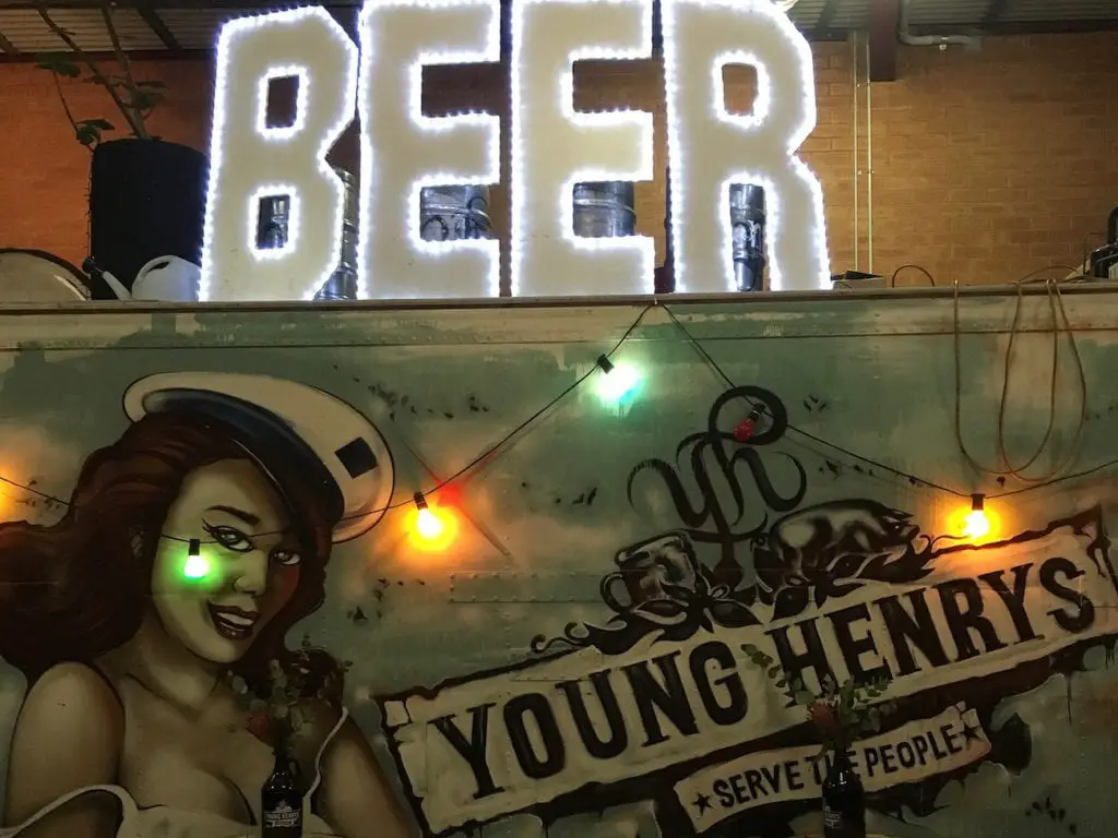 Neon sign spelling 'BEER' mounted on a graffiti-adorned wall with a vintage truck beneath, illustrating Sydney's lively craft beer scene at a local brewery. Newtown has some of the best Sydney nightlife options.