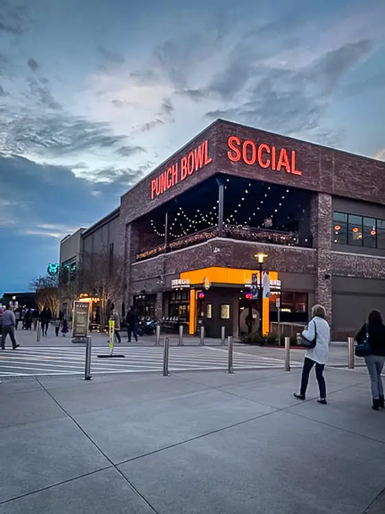 The entrance of Punch Bowl Social, an entertainment venue, with its name in red neon lights above the entrance, and people visible in the vicinity. Add Punchbowl Social to your weekend in Atlanta itinerary - it's a fun place for a night out.