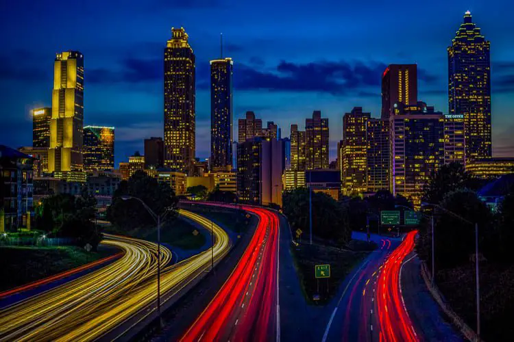 A twilight view of Atlanta’s skyline with illuminated skyscrapers and streaks of red and white lights from traffic on the highway. A weekend in Atlanta is a great amount of time to discover the best of the city.