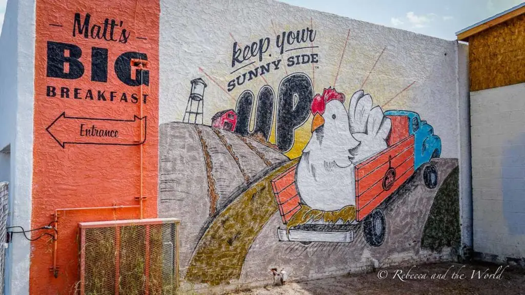 A vibrant mural on a wall depicting a cartoon chicken in a blue truck with the words "Keep Your Sunny Side Up". Matt's Big Breakfast is one of the most popular places to eat in Phoenix.
