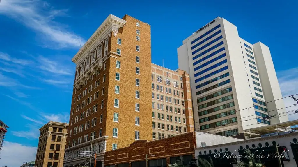 A cityscape with various buildings, including a historic brick building and modern high-rises against a blue sky. Phoenix's downtown area is easy to get around, but you'll need a car to visit the outskirts of the city.