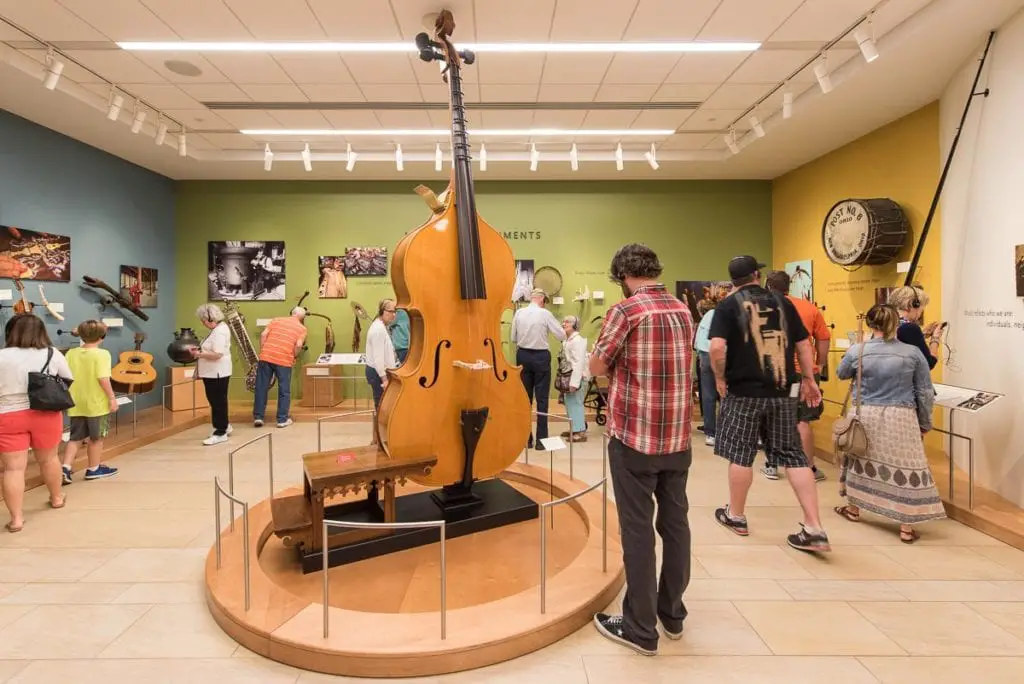 Visitors observing a collection of musical instruments, including a large upright bass, in a museum exhibit. The Musical Instrument Museum in Phoenix is a must-visit on a weekend in Phoenix itinerary.