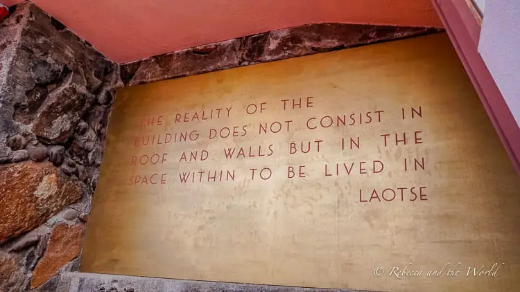 An indoor wall inscription quoting Lao Tse, "The reality of the building does not consist in the roof and walls but in the space within to be lived in," written in elegant, script font. One of the best Scottsdale attractions is Taliesen West.