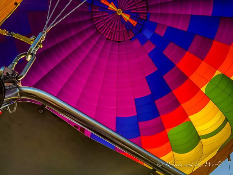 A vibrant and colorful close-up inside view of a hot air balloon, showing the intricate weave of the balloon's fabric in bright shades of blue, red, orange, and green.