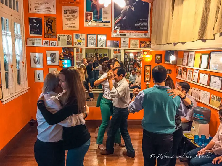 Several couples in a small orange room take in a tango lesson - the people and culture are one of the reasons why you should visit Argentina