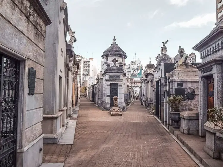 The historic Recoleta Cemetery in Buenos Aires with elaborate mausoleums lining the walkway under a cloudy sky. Recoleta Cemetery in Buenos Aires, Argentina, is fascinating to wander through.