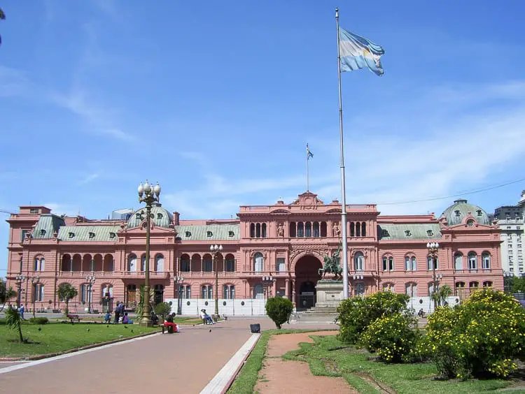 The pink façade of the Casa Rosada, the executive mansion and office of the President of Argentina, with the Argentine flag flying above. Visiting the Casa Rosada and should be one of the first things to do in Buenos Aires for first-time visitors.