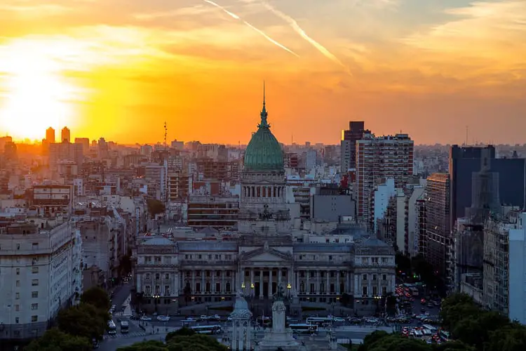 Sunset view over the skyline of Buenos Aires with the dome of the National Congress building prominent against the vibrant orange sky. Buenos Aires is a beautiful city to visit - there's plenty of things to do to add to your Buenos Aires itinerary.