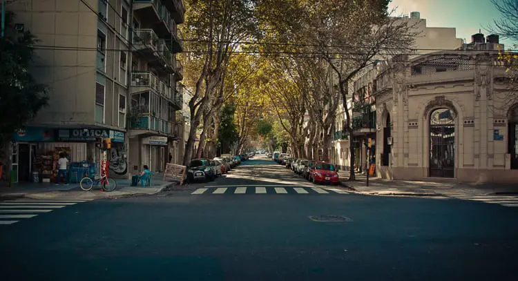 A quiet, tree-lined street in Buenos Aires during the day, with cars parked along the sidewalk and a blue bicycle in the foreground. Wondering what to do in Buenos Aires? You should definitely wander the cool neighbourhood of Palermo.