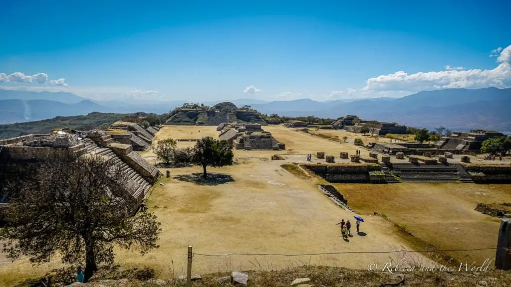 Panoramic view of the ancient Zapotec ruins of Monte Albán on a clear day with mountains in the distance. Monte Alban is a great day trip from Oaxaca - it's a must-visit to see this centuries-old site.