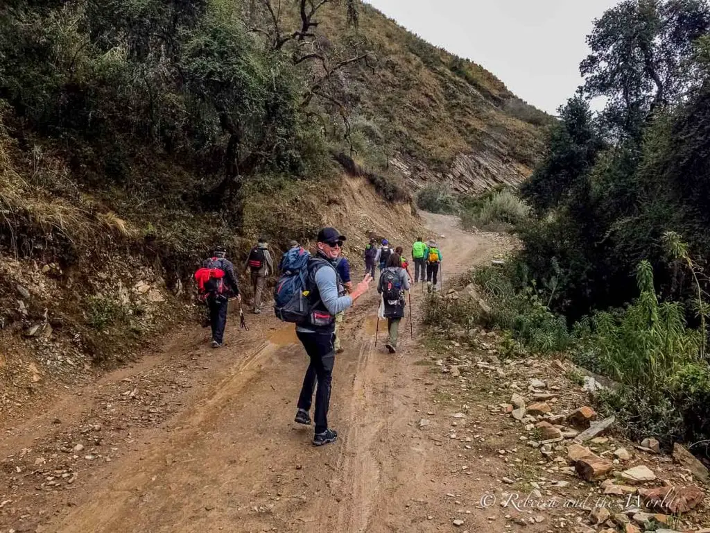 Group of hikers with backpacks walking along a dirt trail surrounded by dense green vegetation in the Salkantay region. If you're planning to do the Salkantay Trek, this Salkantay Trek packing list will have you covered - from the clothing and gear you need, down to the right things to put in your first aid kit.