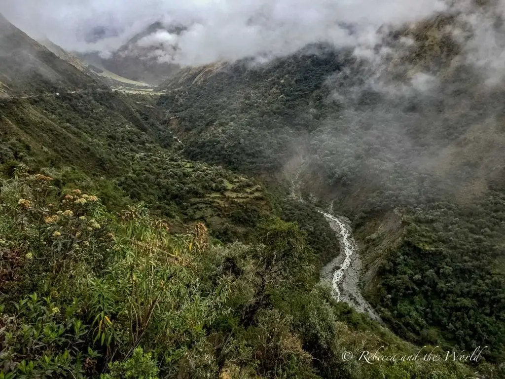 Misty mountain landscape with a narrow river winding through the valley, viewed from a high elevation on the Salkantay Trek. The Salkantay Trek in Peru leads to Machu Picchu - and includes a lot of stunning scenery along the way.