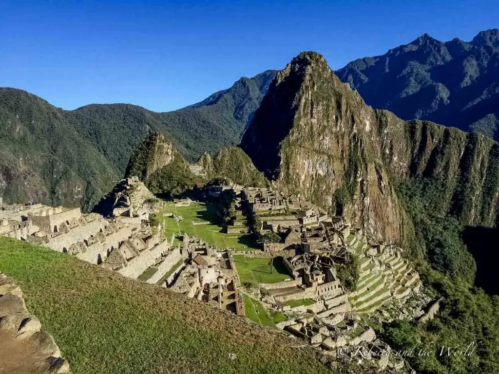 Aerial view of Machu Picchu showcasing the ancient ruins with the Huayna Picchu mountain in the background and lush greenery surrounding the site. Nothing can prepare you for the wonder and awe you'll feel upon seeing Machu Picchu for the first time!