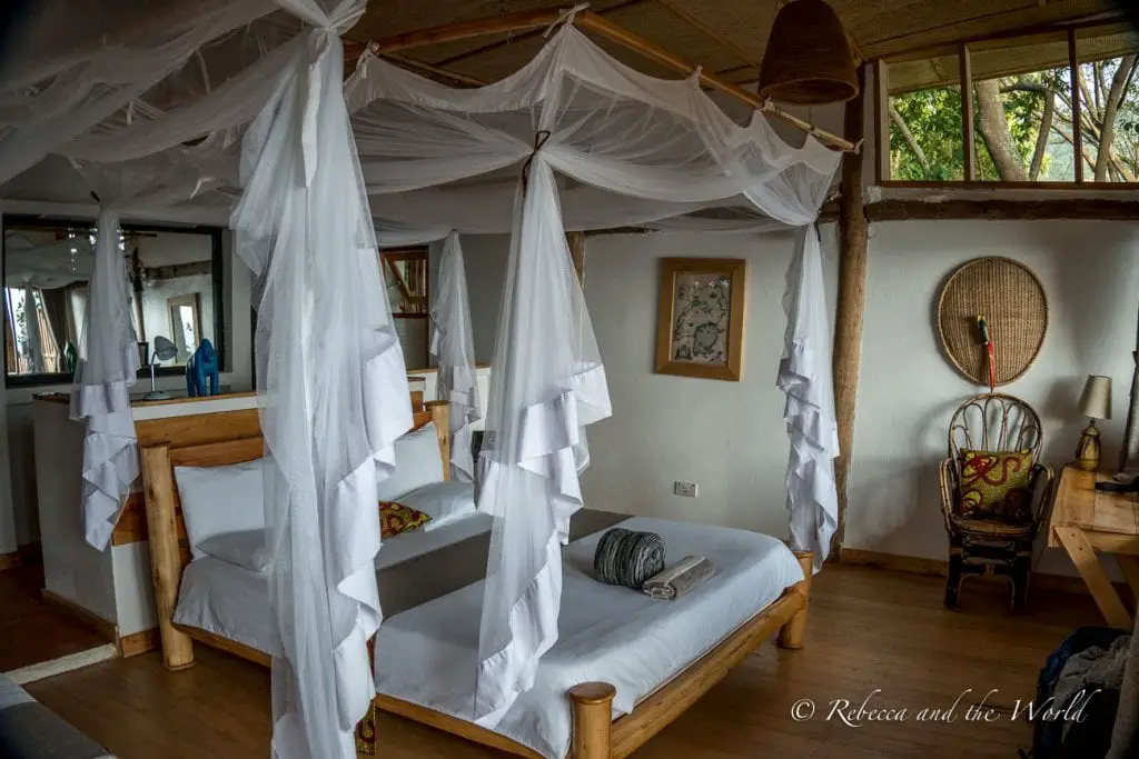 A cosy lodge room with a large bed covered with white mosquito nets, wooden furniture, and a warm, inviting atmosphere with natural light coming through the windows. I loved the fresh, modern rooms at Mutanda Lake Resort in Uganda.