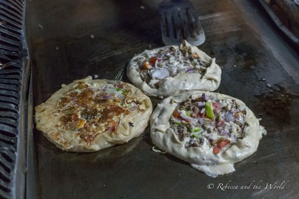 Two Zanzibar pizzas cooking on a griddle, a local street food specialty. Zanzibar pizza is a local specialty and a must-try when you visit Zanzibar.
