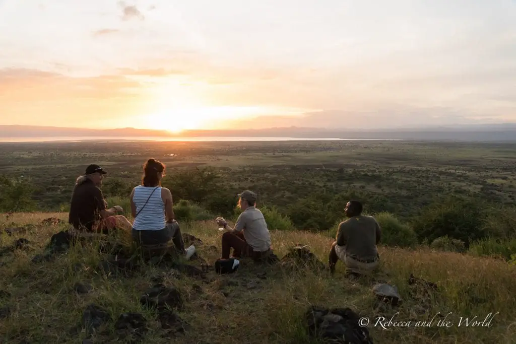 A group of people sitting on the ground, enjoying a sunset with a wide view of the plains stretching out to the horizon. Isoitok Camp Manyara was one of my favourite places to stay in Tanzania.