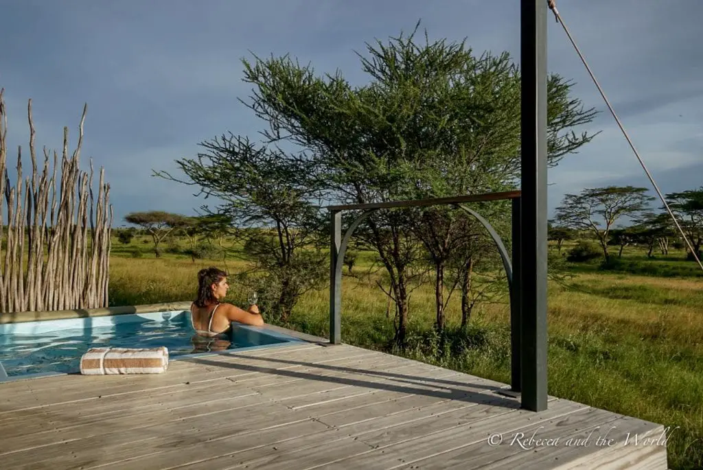 A woman (the author of this article) relaxing in a plunge pool on a wooden deck, overlooking a savanna with trees and grassland. Each of the tents at Lemala Nanyukie has a private plunge pool.
