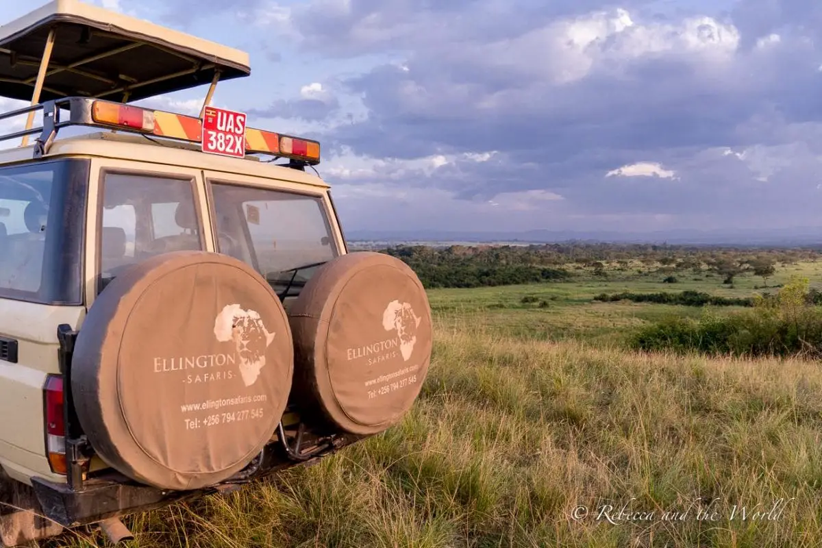 Safari vehicle with covered spare tires parked at a scenic overlook with expansive views of green plains and distant hills under a cloudy sky. Enjoying the views in Queen Elizabeth National Park with Ellington Safaris.