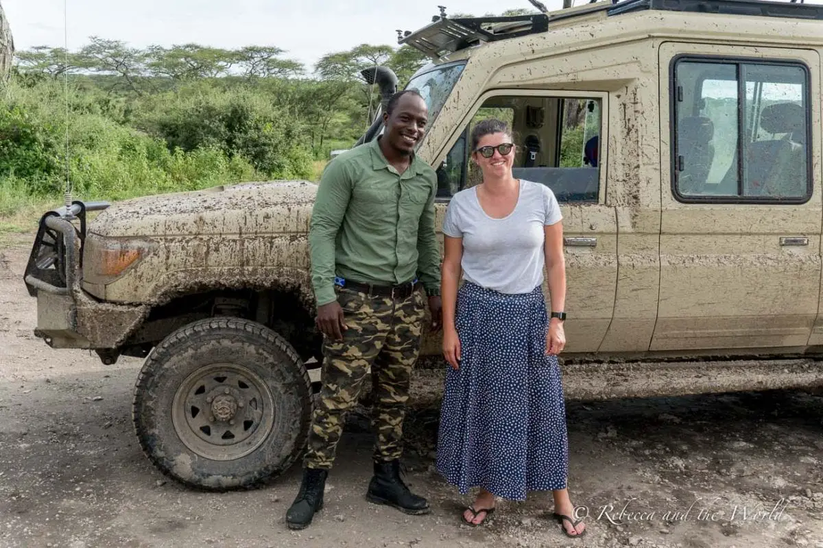 A man and a woman - the author of this article - smiling and standing next to a mud-splattered safari vehicle, showcasing the rugged terrain experienced during the safari. Me with my guide Baraka from Wild & Me Safaris (now called Safari Republic) in Tanzania.