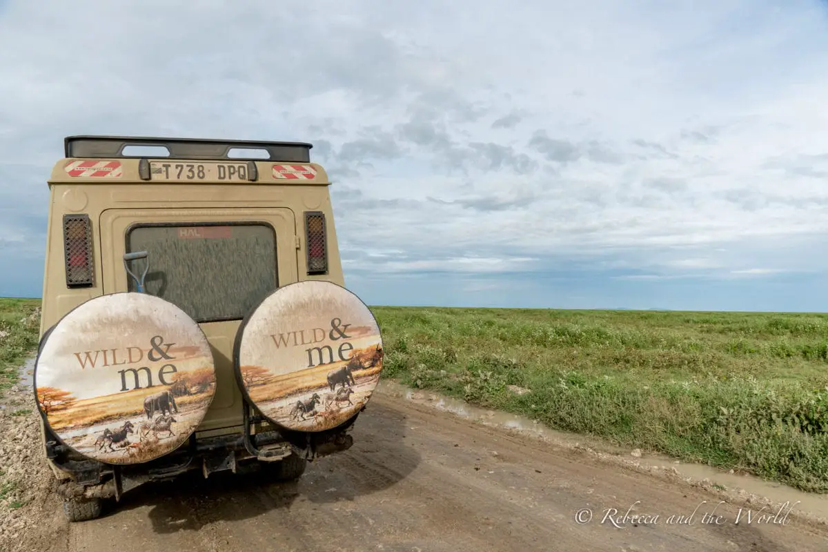 The back of a Wild & Me safari vehicle parked on the side of a dirt road in Tanzania.