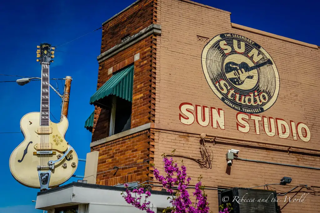 A large guitar sign and a mural with the words "Sun Studio, Memphis, Tennessee" adorn the side of a brick building. One of the best things to do in Memphis is visit the famous Sun Studio.