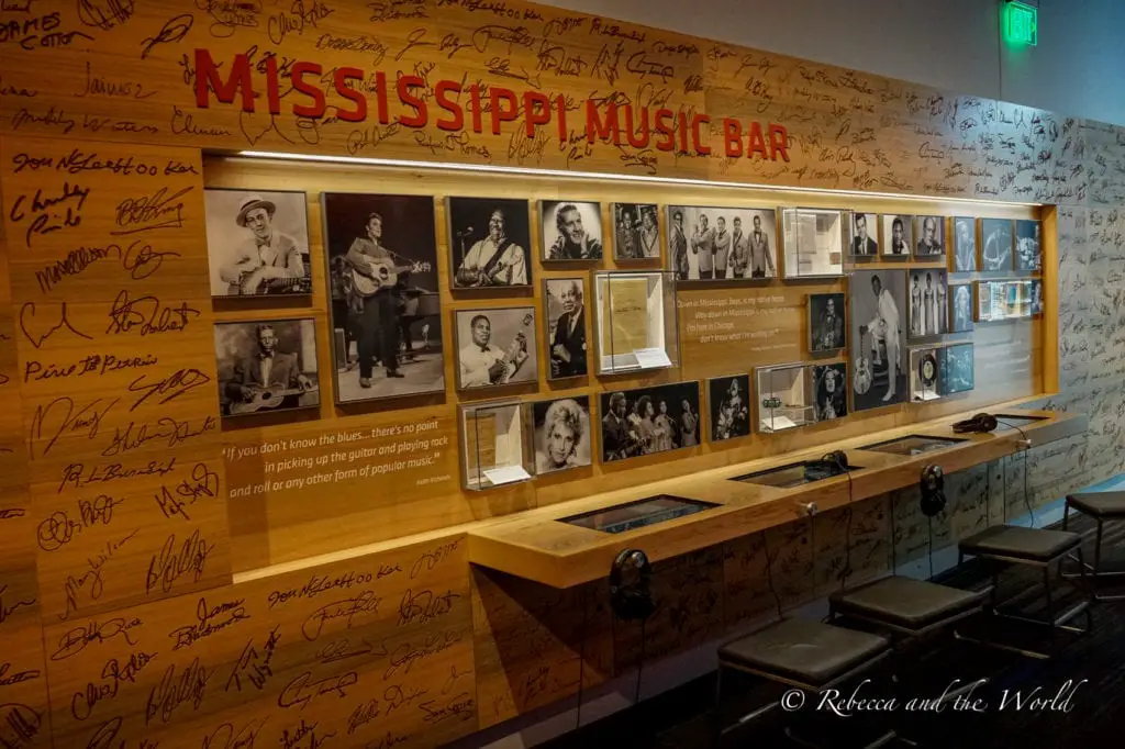 The Mississippi Music Bar interior, with a long wooden counter, stools, and walls covered with signatures, photographs of musicians, and blues-themed decorations. Inside the GRAMMY Museum Mississippi in Cleveland.