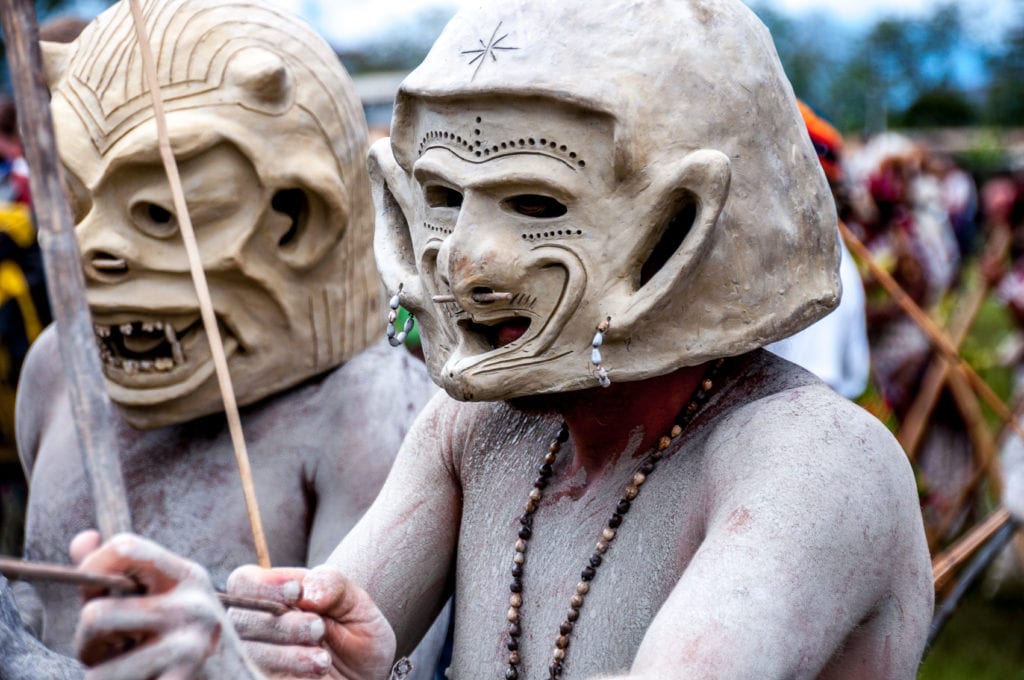 Close-up of two Papua New Guinean men wearing traditional mud masks and costumes during a cultural festival. These are the Asaro Mud Men. There are thousands of different cultures in Papua New Guinea to learn about.