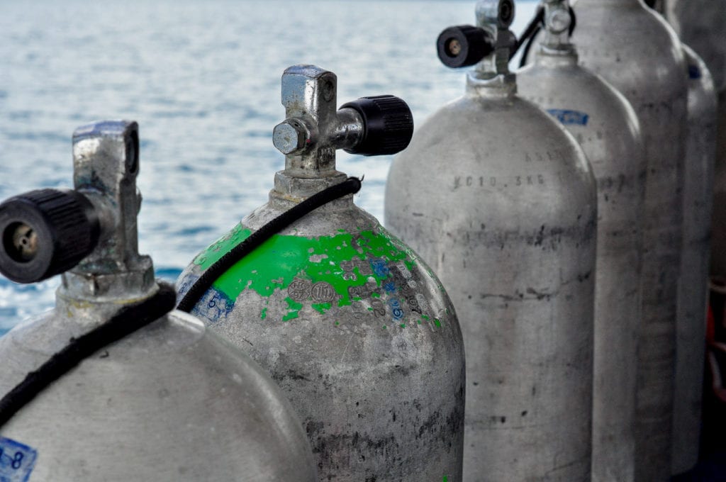 Row of used scuba diving air tanks on a boat. Diving in Papua New Guinea is a popular activity.