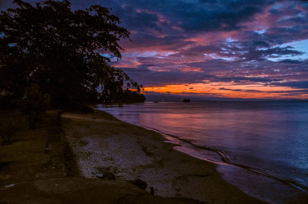 Stunning sunset at a beach with violet and orange skies reflecting in the tranquil sea waters of Papua New Guinea. PNG sunsets are magical.